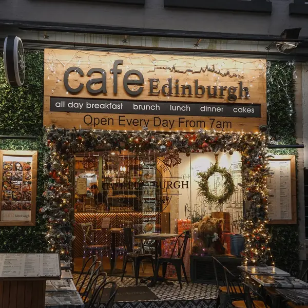 The cafe frontage lit up at dusk, with plants either side of the doorway