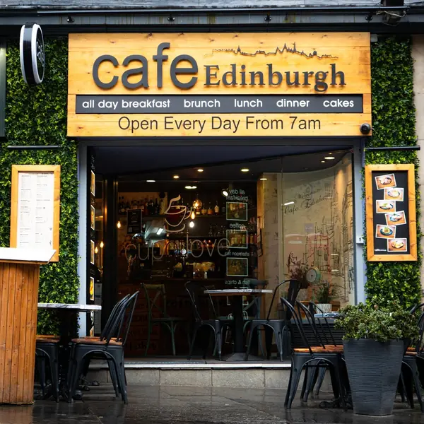 The cafe sign above the door, with a sandwich board out on the pavement