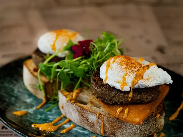Poached eggs on a toasted muffin with herbs and a hollandaise-dressed salad