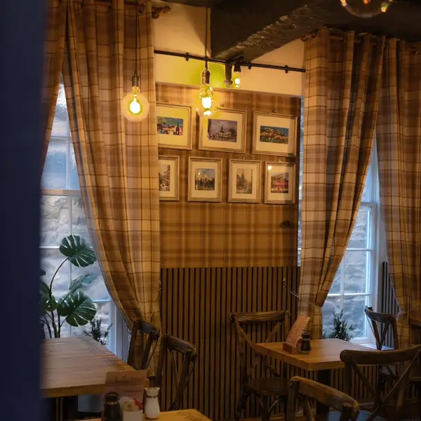 Chairs drawn up to a table beside a tall window with heavy plaid curtains