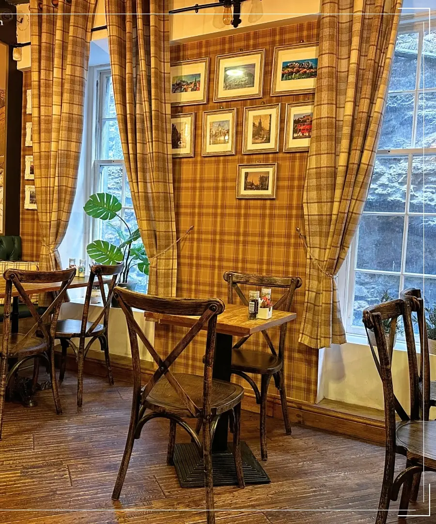 The front room before service: bare tables, framed prints and plaid curtains at the windows
